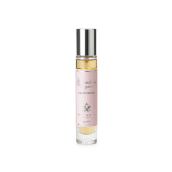Perfume bottle with a pink label, silver cap, and pale yellow liquid seen through clear glass.