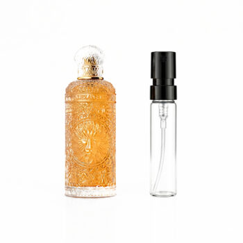 Luxurious ornate perfume bottle with orange liquid and lion motif beside a clear spray bottle on a white background, suggesting a fragrance display.