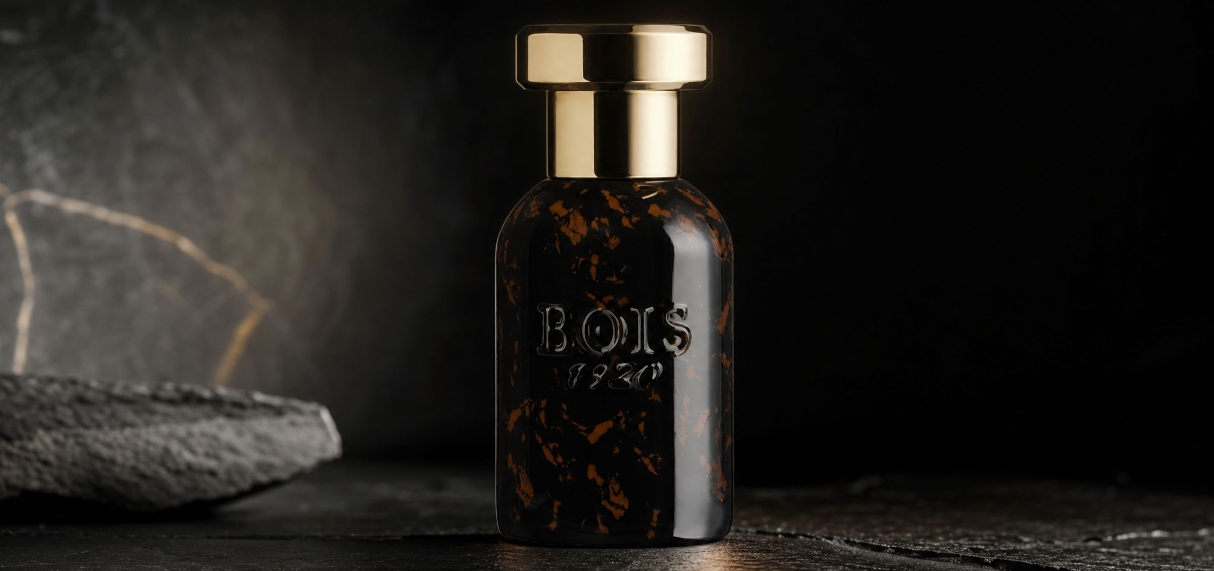 Dark glass perfume bottle with a gold cap, embossed with 'BOSS' on the front, set against a black backdrop.