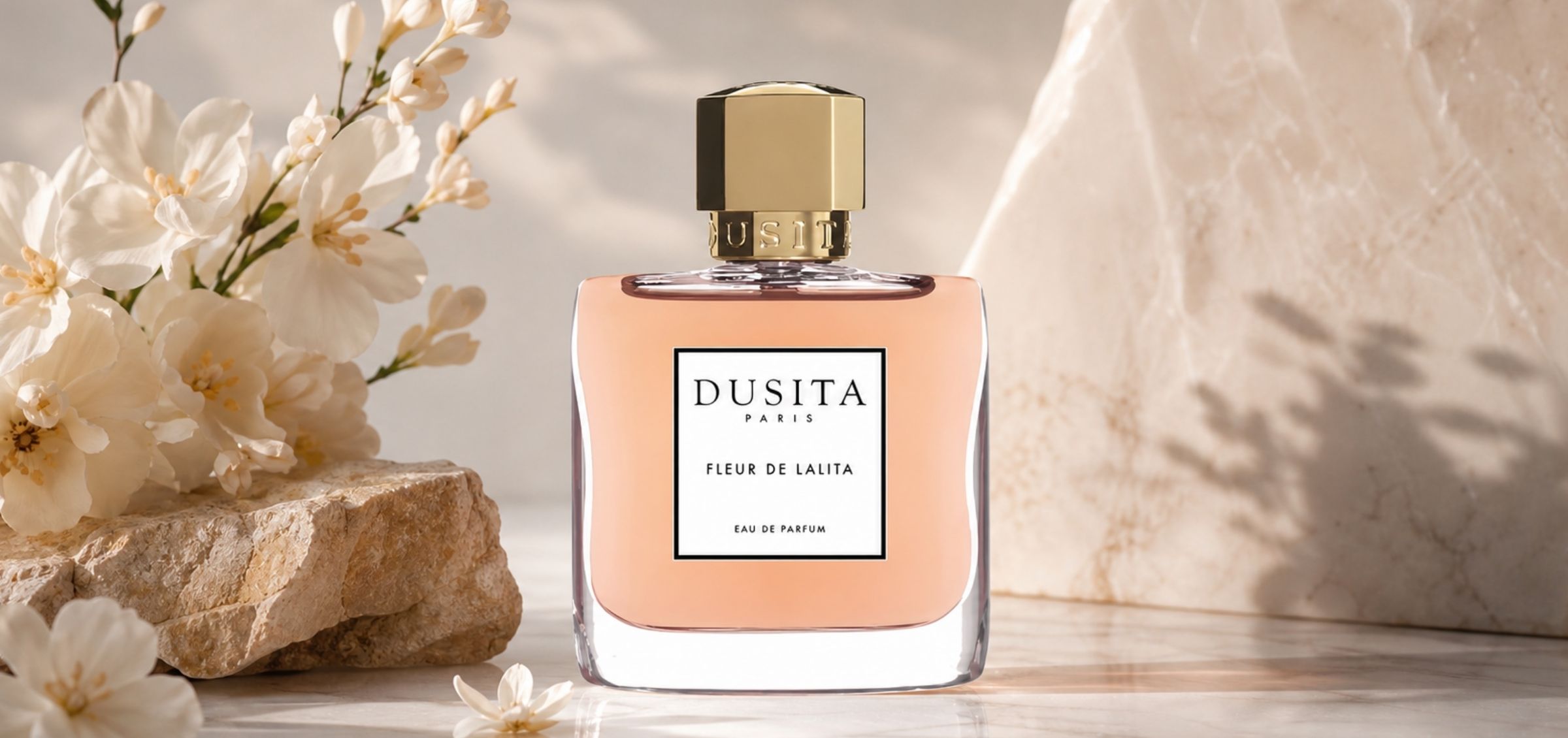inpresioa-perfumy-fleur-de-lalita-kiedy-natura-zamienia-sie-w-poezje-kwiaty-harmonia - Inpresioa Perfume bottle labeled Dusita Paris Fleur de Lalita on a stone surface with white flowers in the background