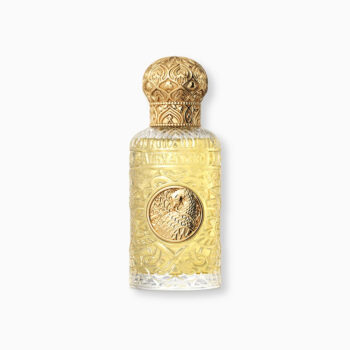 Ornate gold and clear glass perfume bottle with embossed patterns and a circular medallion emblem, topped by a decorative gold cap.